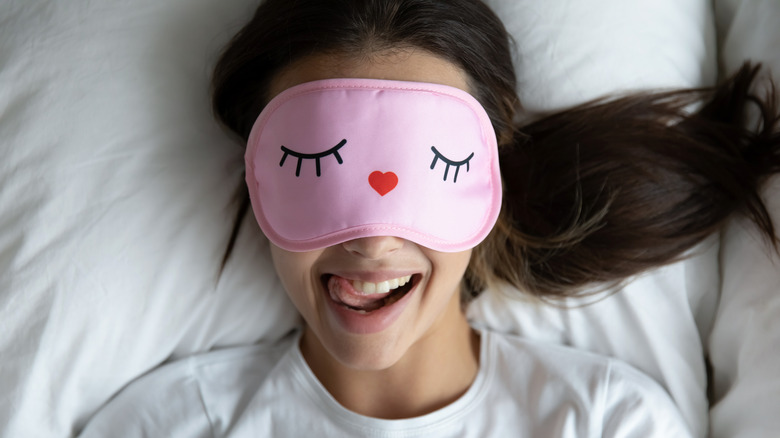 woman laying in bed wearing sleep mask