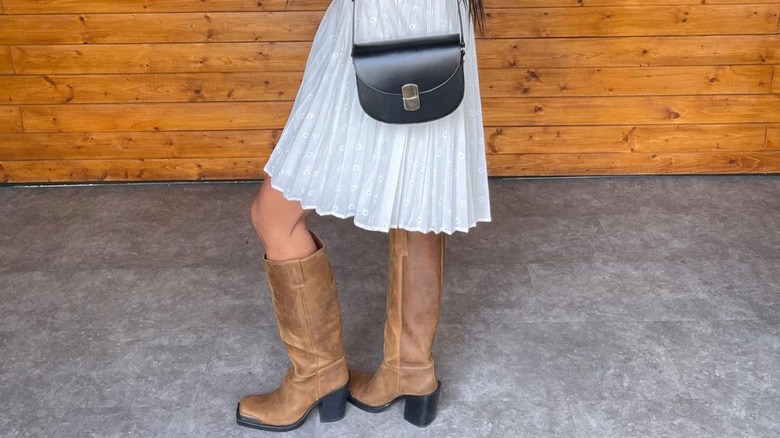 faded brown tall boots and black leather purse