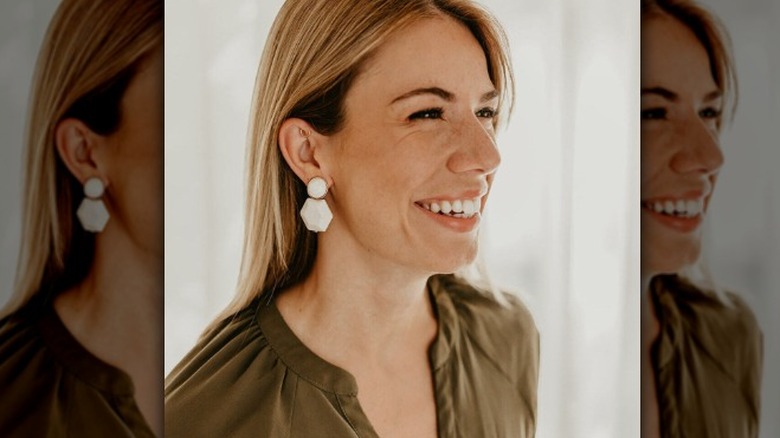 A woman wearing white statement earrings