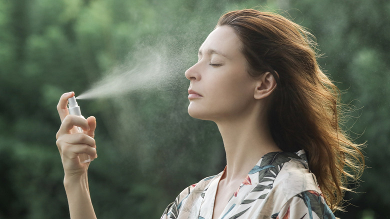 Woman spraying on facial mist outdoors
