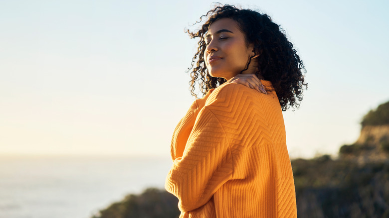 Woman standing outside hugging herself 