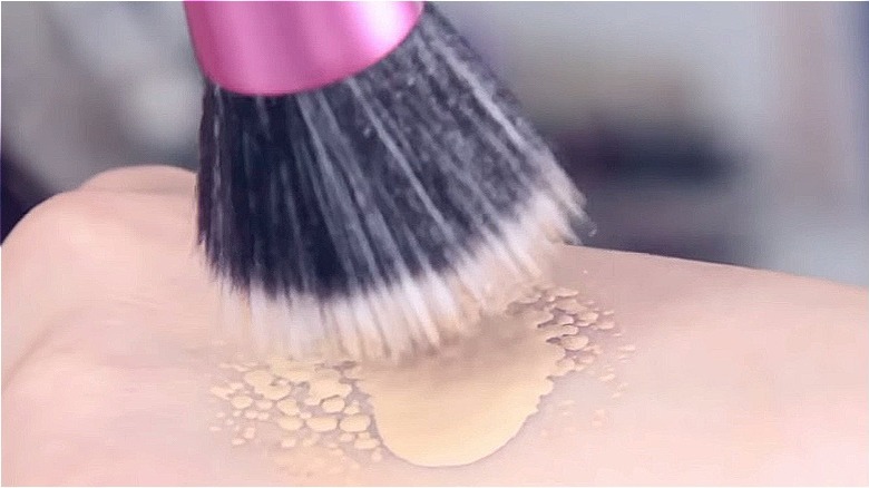 woman dabbing stippling brush into foundation