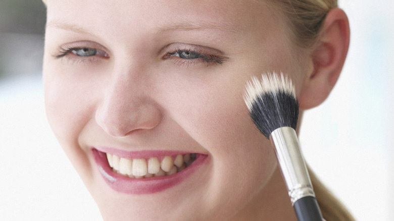 woman applying blush to her face