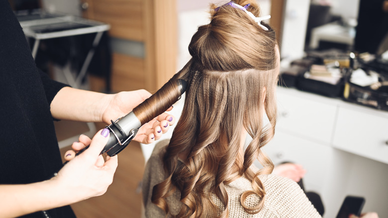 Hairstylist curling a woman's hair