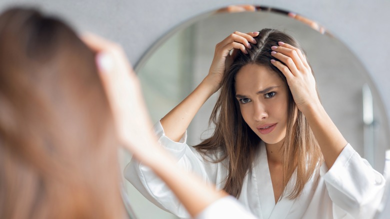 Woman checking scalp in mirror