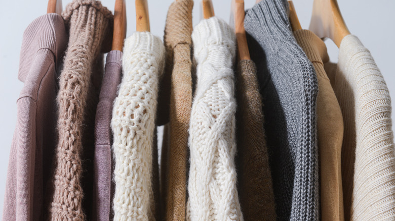 knit sweaters hanging on wooden rack 