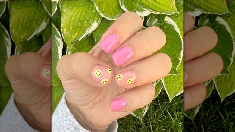 hand with pink and yellow smiley nails