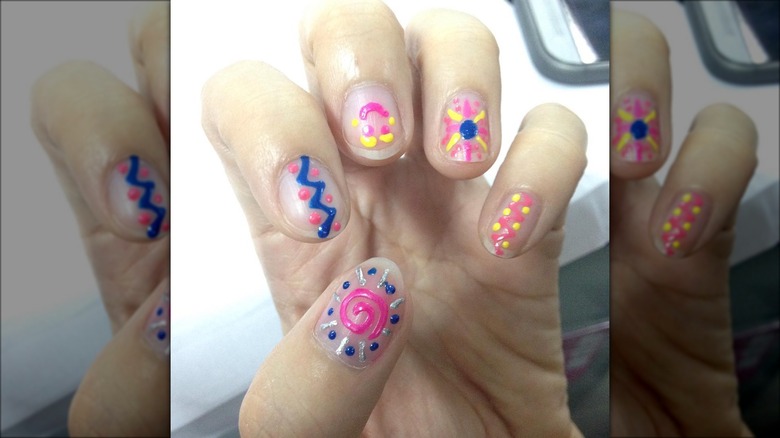 hands with pink yellow blue abstract nails