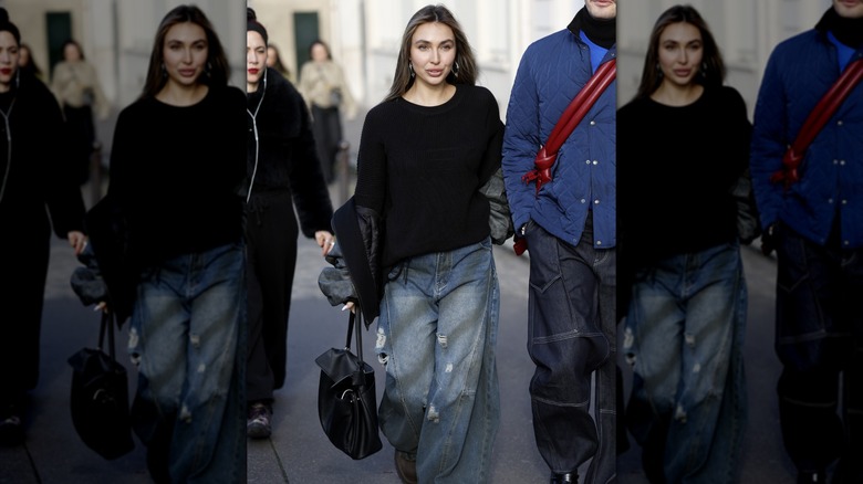 A woman wearing ultra baggy jeans carrying a black bag