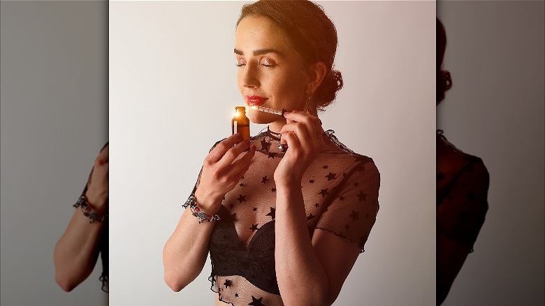 Woman wearing sheer top and smelling essential oil