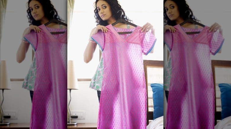 Woman holding pink sheer dress on hanger