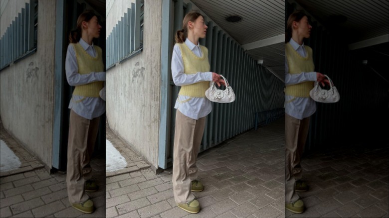 woman wearing yellow sweater vest and beige trousers