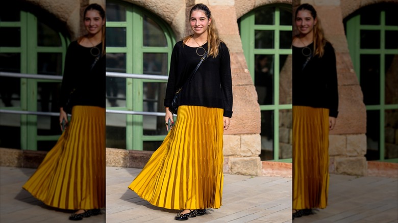 Woman wearing black sweater and yellow maxi skirt