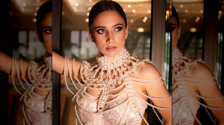 A woman wearing a complex pearl-beaded shawl over her gown.