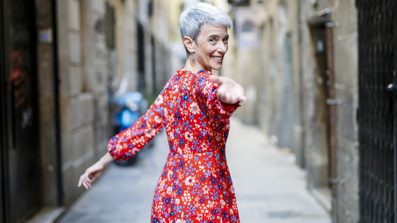 An older woman with white hair wearing a ditsy floral dress.