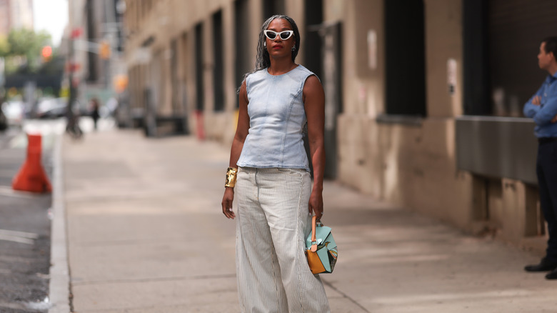 A woman wearing blue denim shirt and striped pants.