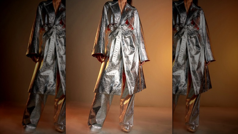 A model poses in a long metallic coat.