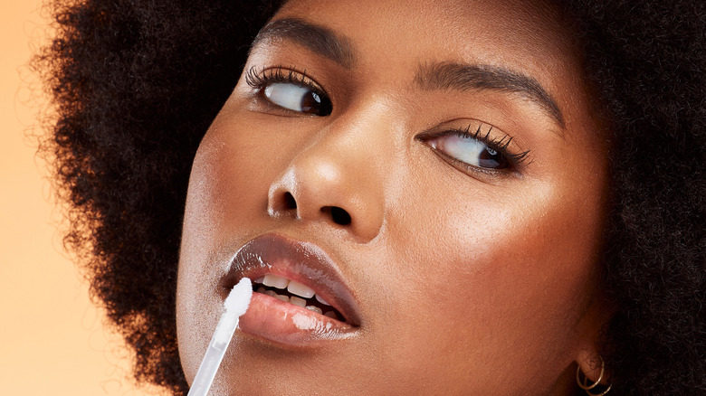 Woman applying clear lip gloss