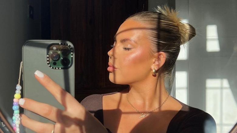 woman with glowing skin taking selfie