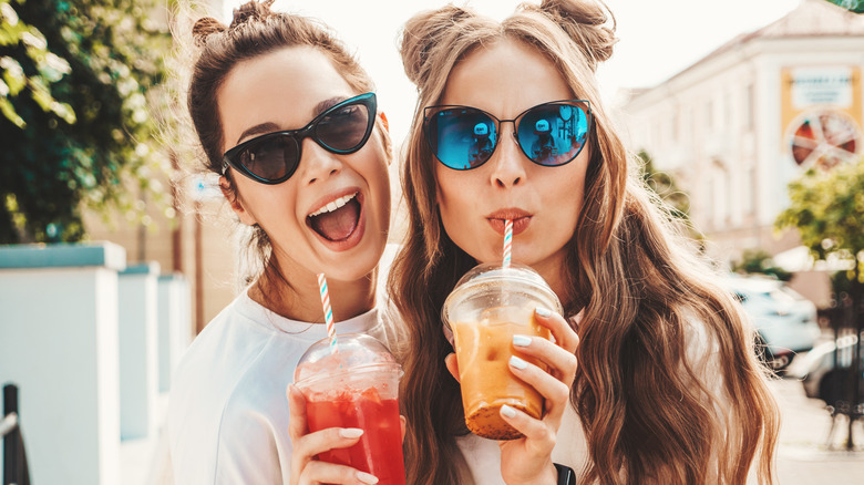 women drinking iced drinks from straws