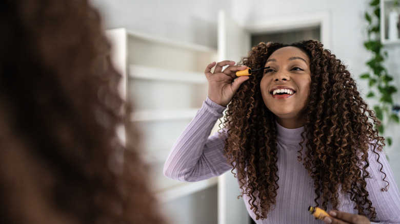 woman applying mascara in the mirror