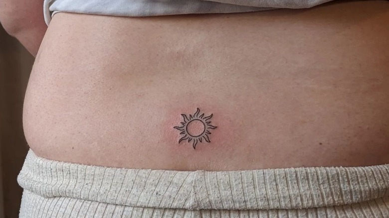 small sun lower back tattoo