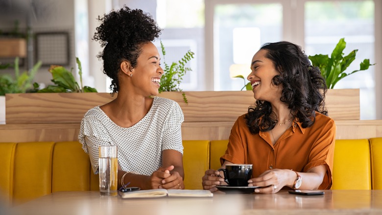 Two women laughing and drinking coffee