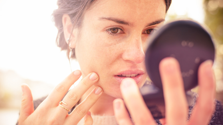 Woman examining skin in compact