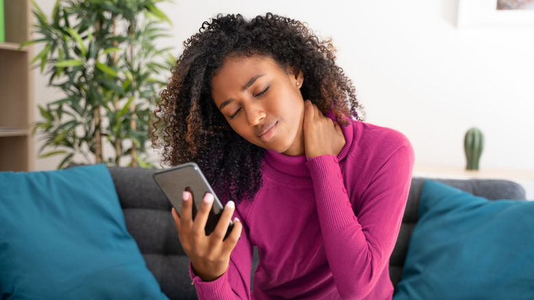 Woman looking at phone with neck pain