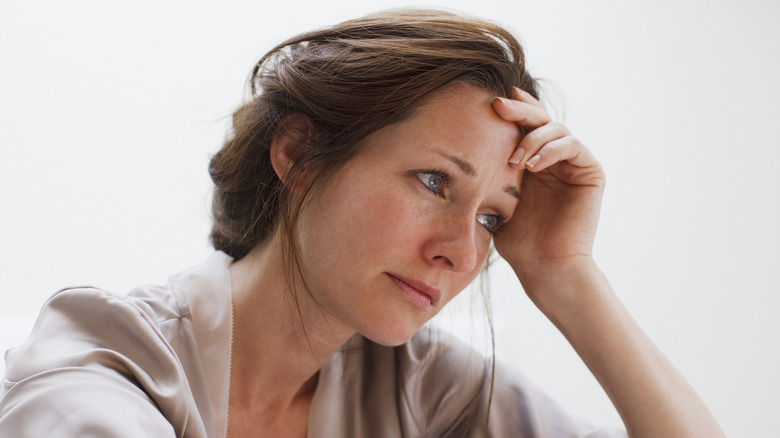 Woman with hand on her head looking thoughtful