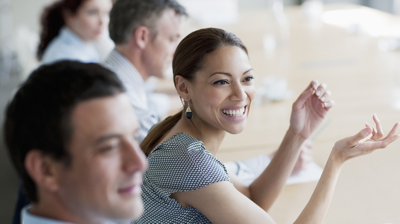 Confident woman smiling with colleagues at meeting