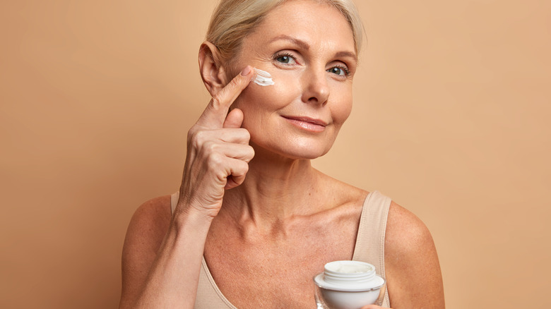 mature woman applying moisturizer 