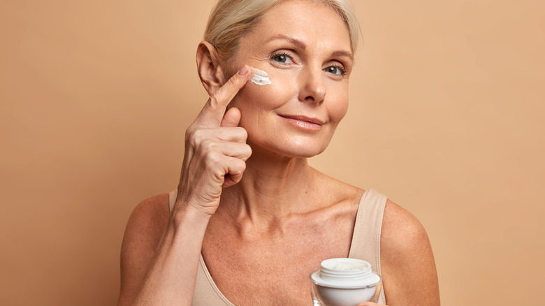 mature woman applying moisturizer