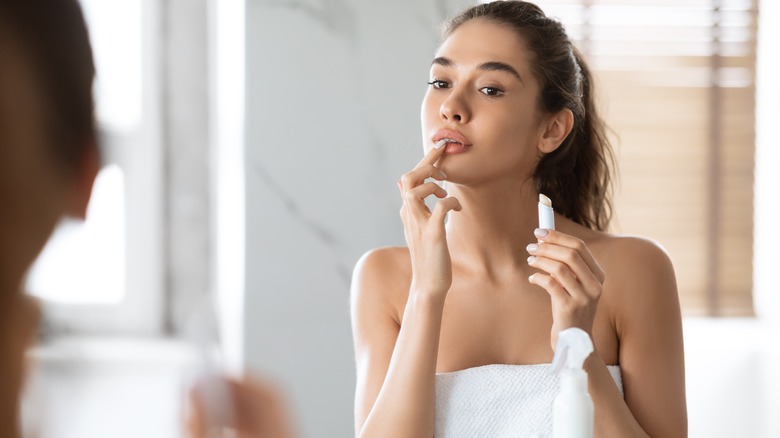 woman putting on lip balm