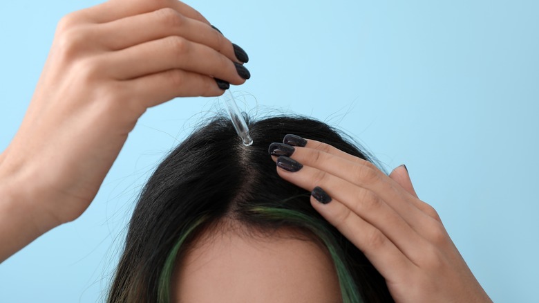 Woman applying serum to scalp