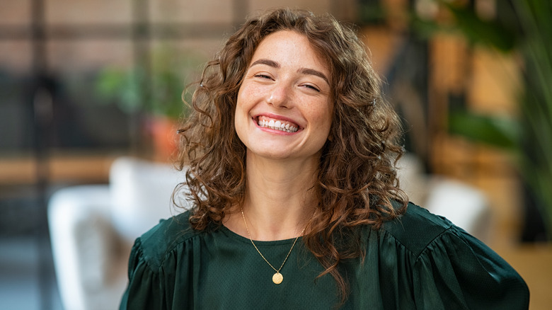 White woman with long curly hair smiling 