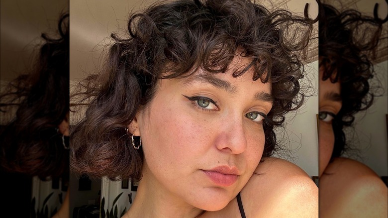 woman with curly french bob bangs