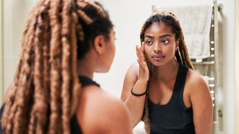 Woman looking at face in mirror