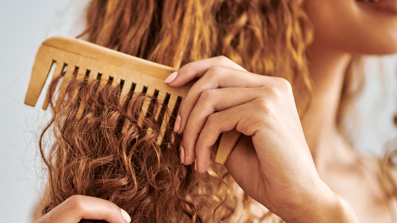 Woman brushing curly hair with comb