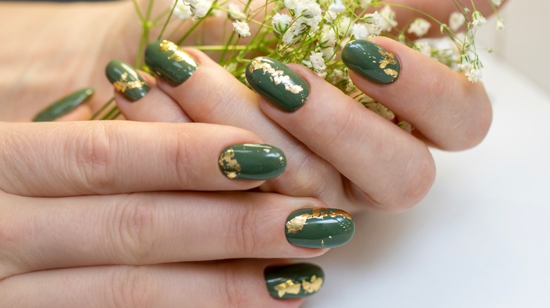 A green manicure with gold foil accents.