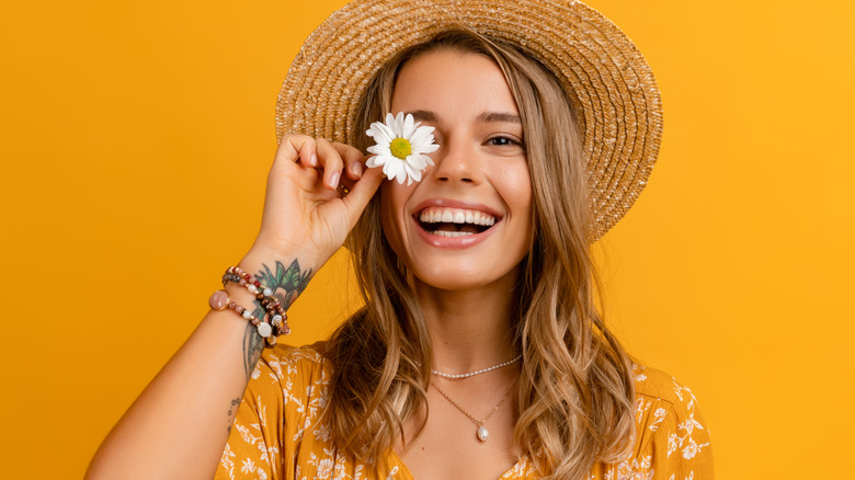 woman smiling with a daisy