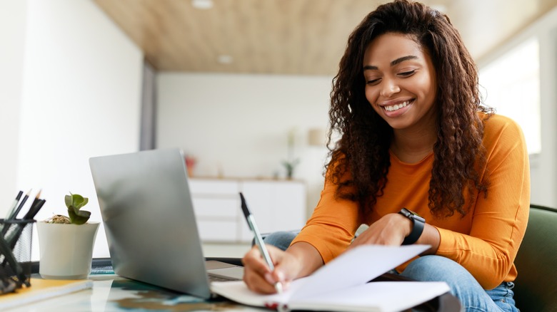 woman smiling while writing in her notebook