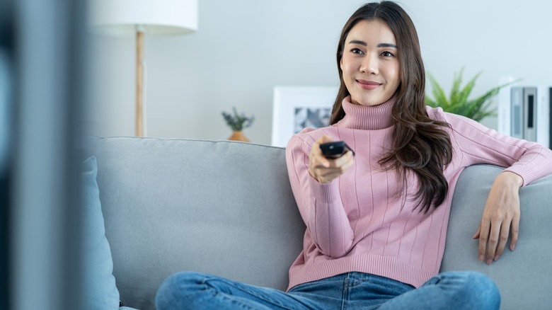 woman using remote controller to watch tv