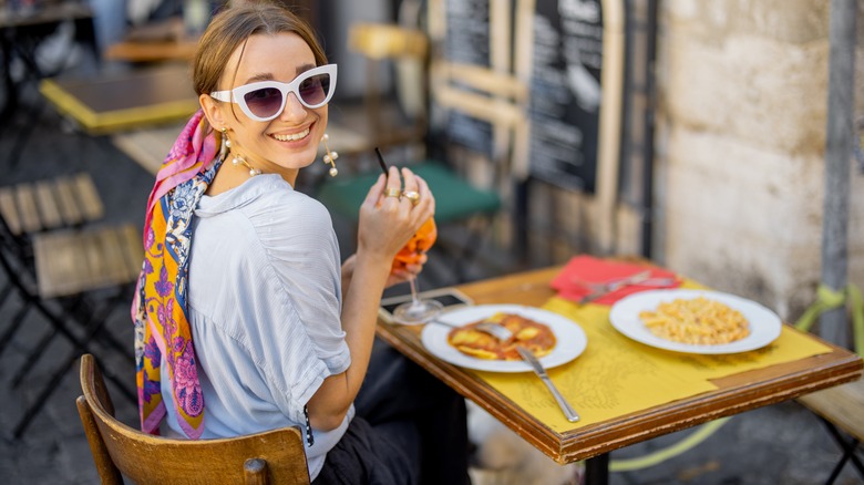 woman eating at dinner with sunglasses