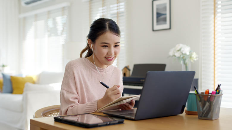 woman on her laptop jotting down notes