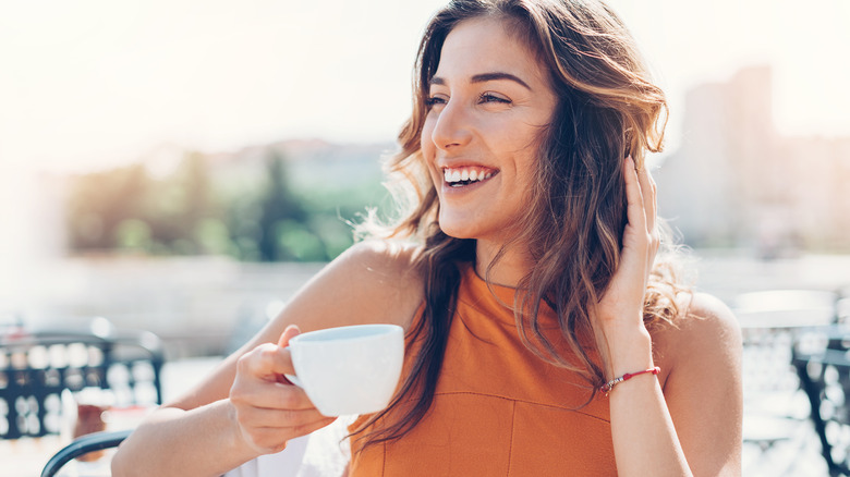 Smiling woman drinking coffee outside