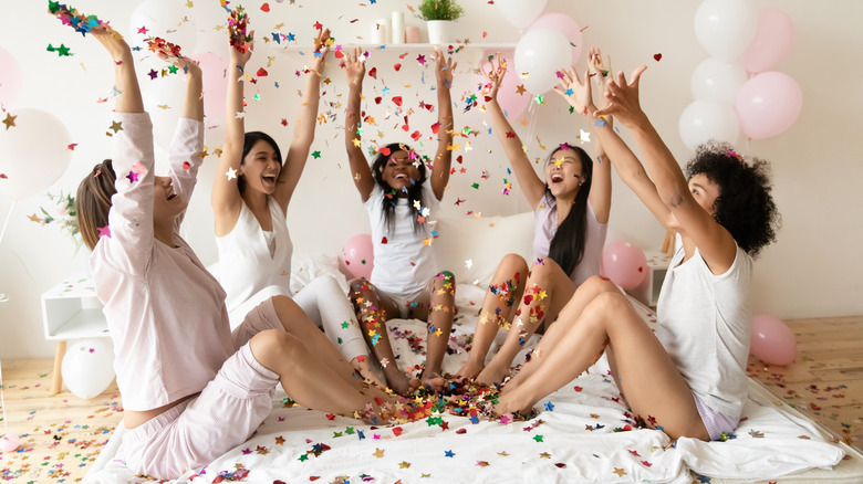 Women throwing confetti at sleepover 