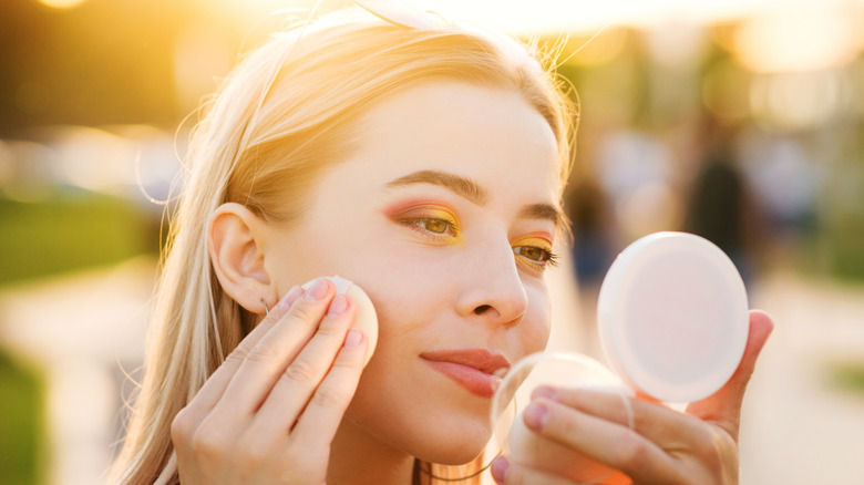 woman finishing makeup in the sun