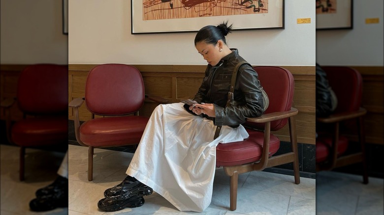 Woman wearing long white skirt and leather jacket