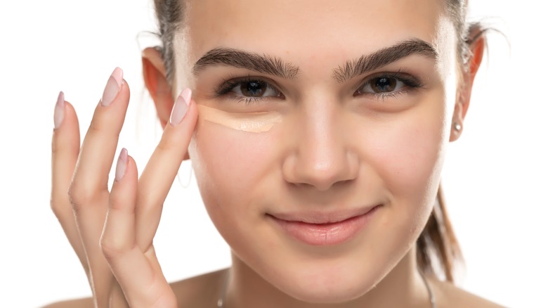 Woman blending concealer with finger